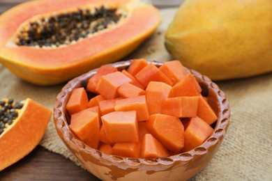 Photo of Tasty whole and cut papaya fruits on wooden table, closeup