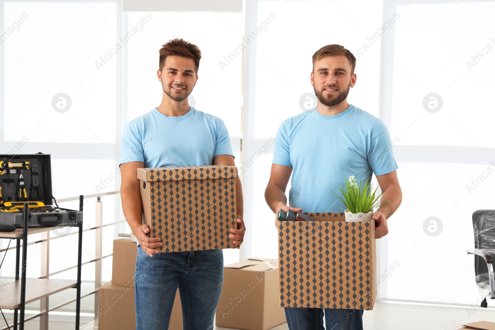 Photo of Professional workers with cardboard boxes in office. Moving service