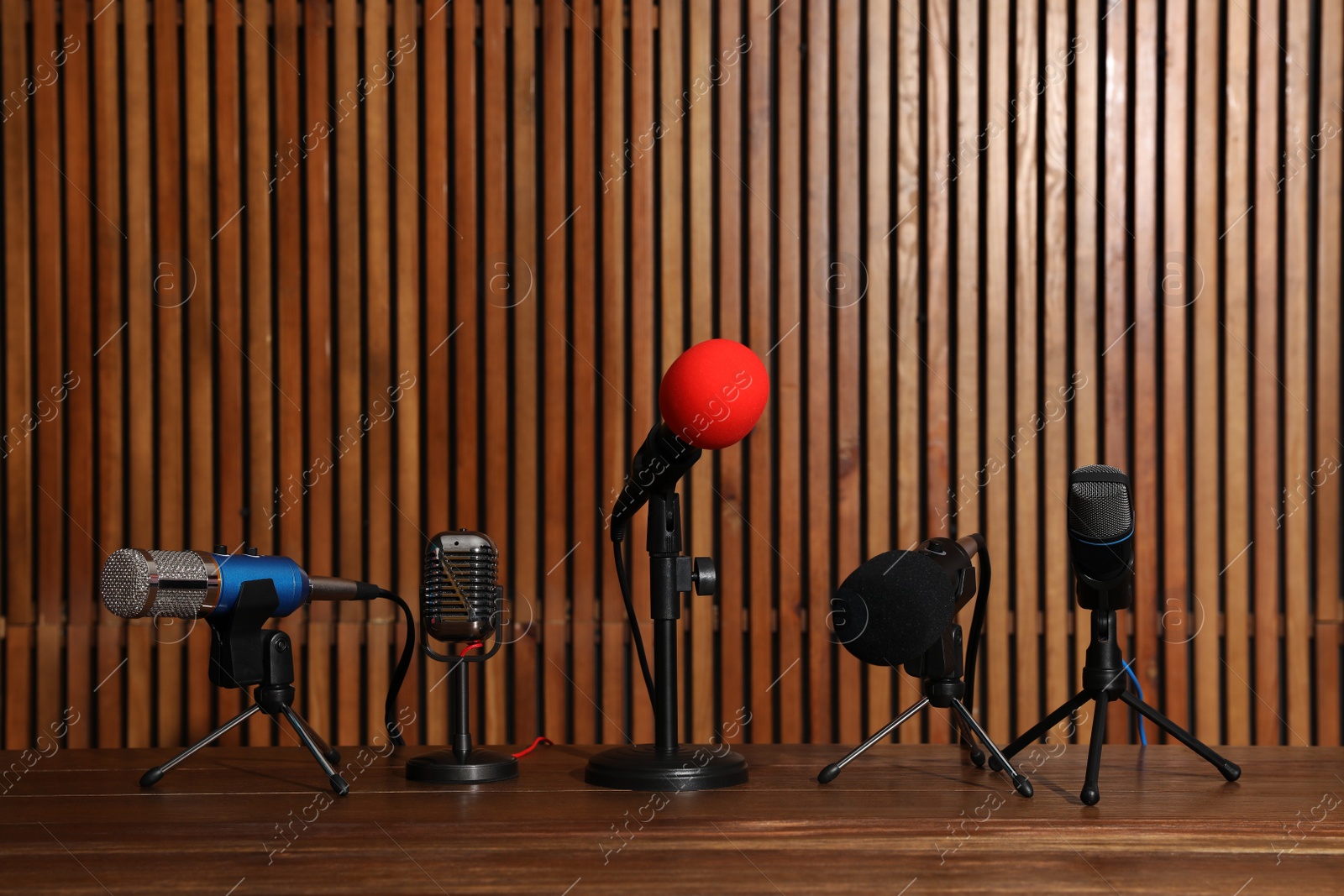 Photo of Set of different microphones on wooden table. Journalist's equipment