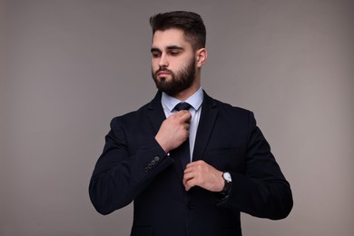 Handsome businessman in suit and necktie on grey background