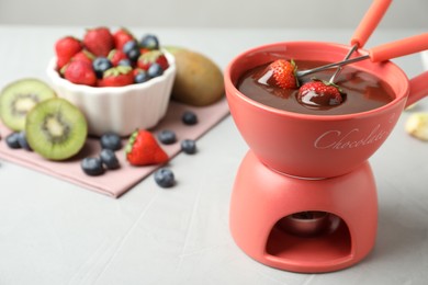 Photo of Fondue pot with chocolate and different products on grey table. Space for text