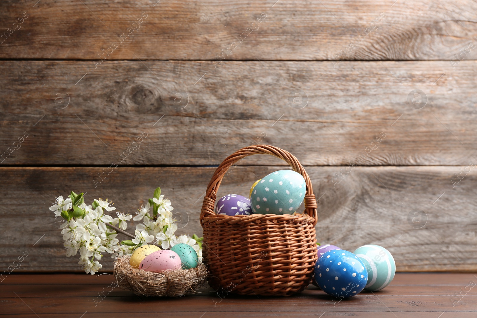 Photo of Composition with painted Easter eggs and blossoming branches on table. Space for text