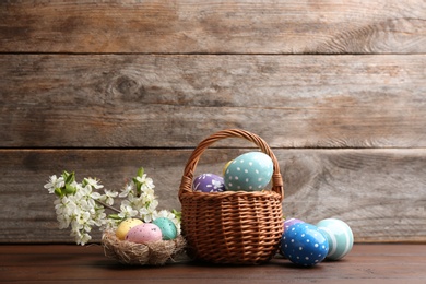 Photo of Composition with painted Easter eggs and blossoming branches on table. Space for text