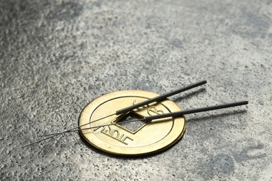 Photo of Acupuncture needles and Chinese coin on grey textured table, closeup. Space for text