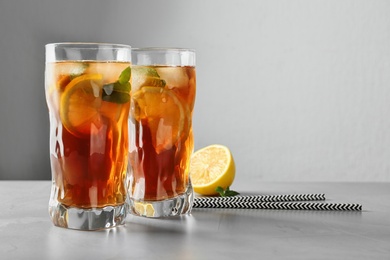 Photo of Glasses of refreshing iced tea on table against grey background. Space for text
