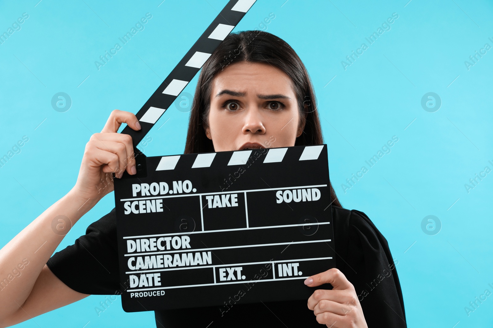 Photo of Emotional actress with clapperboard on light blue background. Film industry