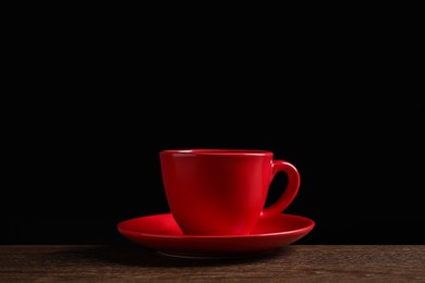 Photo of Red cup on wooden table against black background