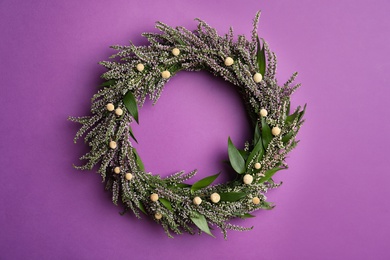 Beautiful heather wreath on purple background, top view. Autumnal flowers