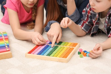 Mother and children playing with different colorful cubes and equations on floor, closeup. Learning mathematics with fun