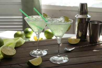 Photo of Delicious Margarita cocktail in glasses and lime on wooden table, closeup