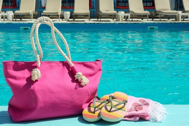 Beach accessories on wooden deck near swimming pool. Space for text