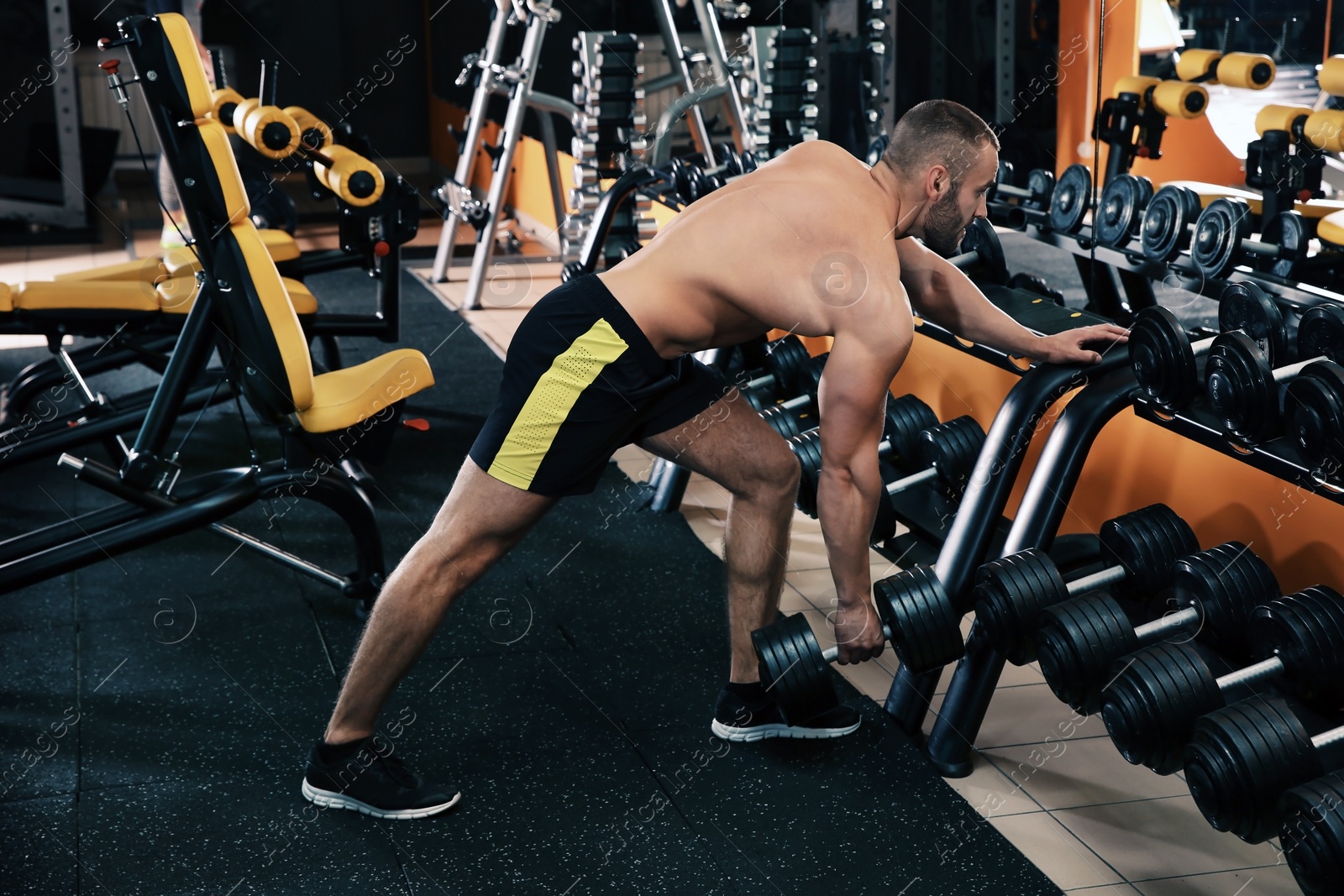 Photo of Strong young man lifting dumbbell in gym