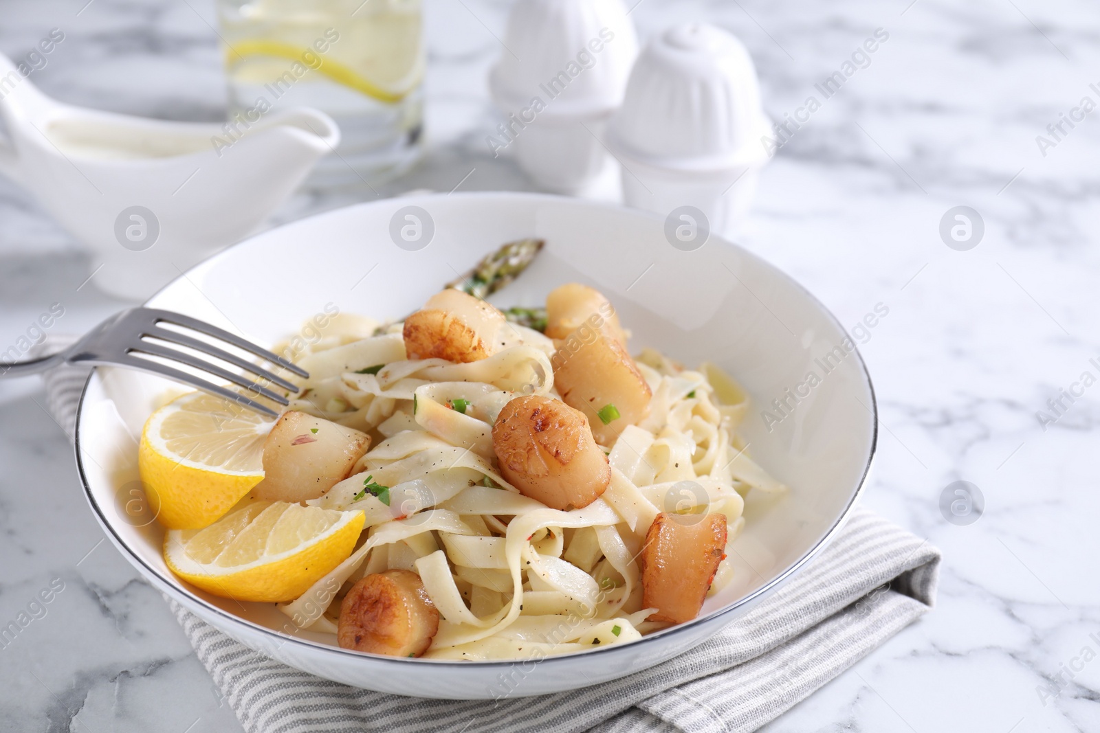 Photo of Delicious scallop pasta served on white marble table, closeup