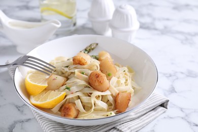 Photo of Delicious scallop pasta served on white marble table, closeup