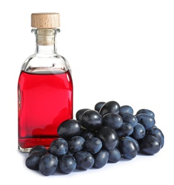 Photo of Bottle with wine vinegar and fresh grapes on white background