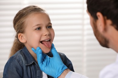 Doctor in medical glove examining girl`s oral cavity indoors