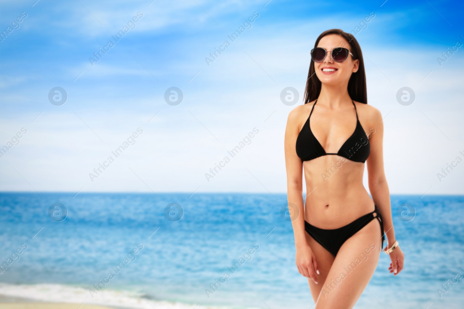 Image of Pretty sexy woman with slim body in stylish black bikini near ocean on sunny day, space for text