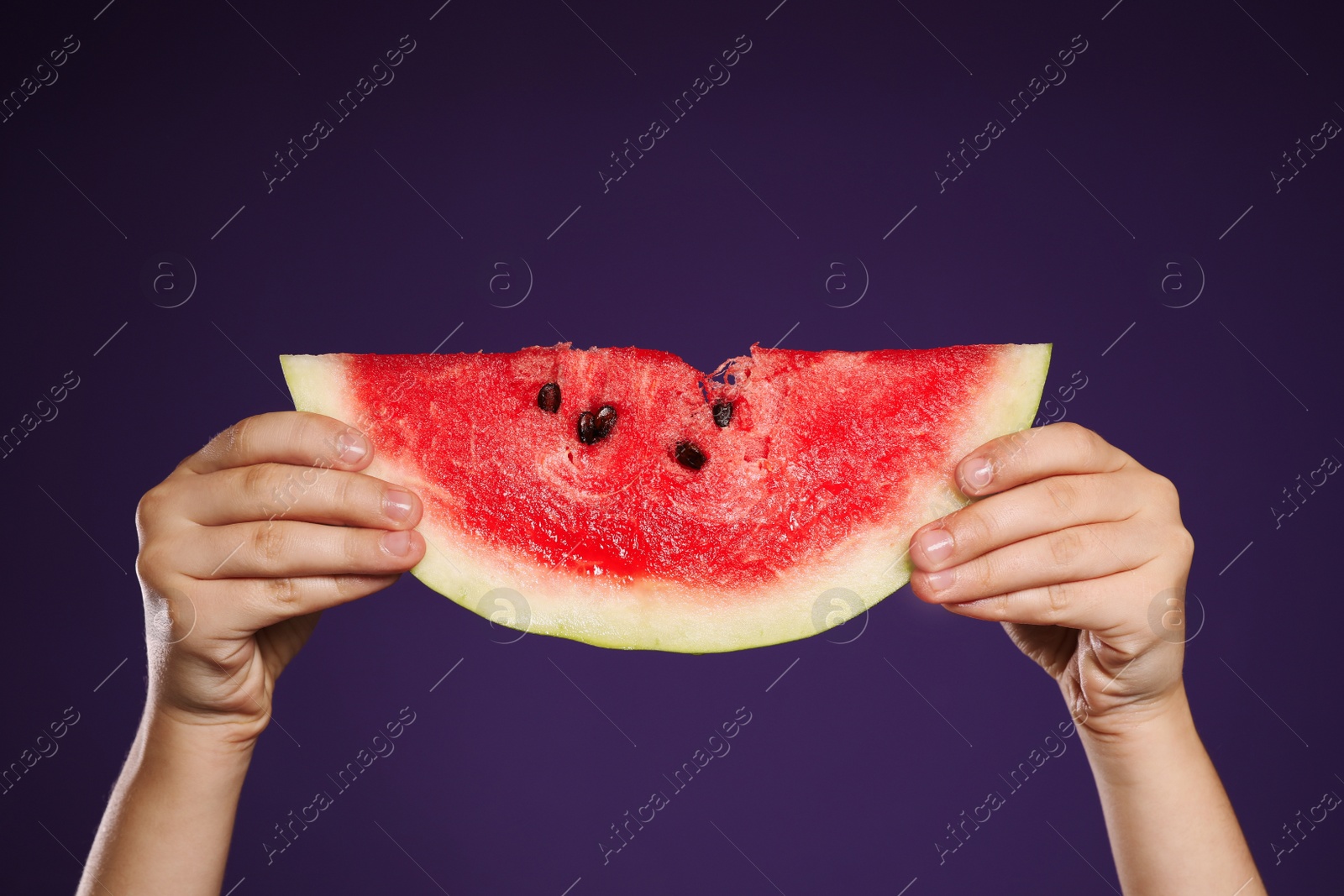 Photo of Child holding watermelon on purple background, closeup of hands