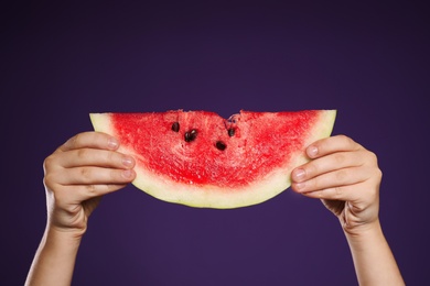 Photo of Child holding watermelon on purple background, closeup of hands