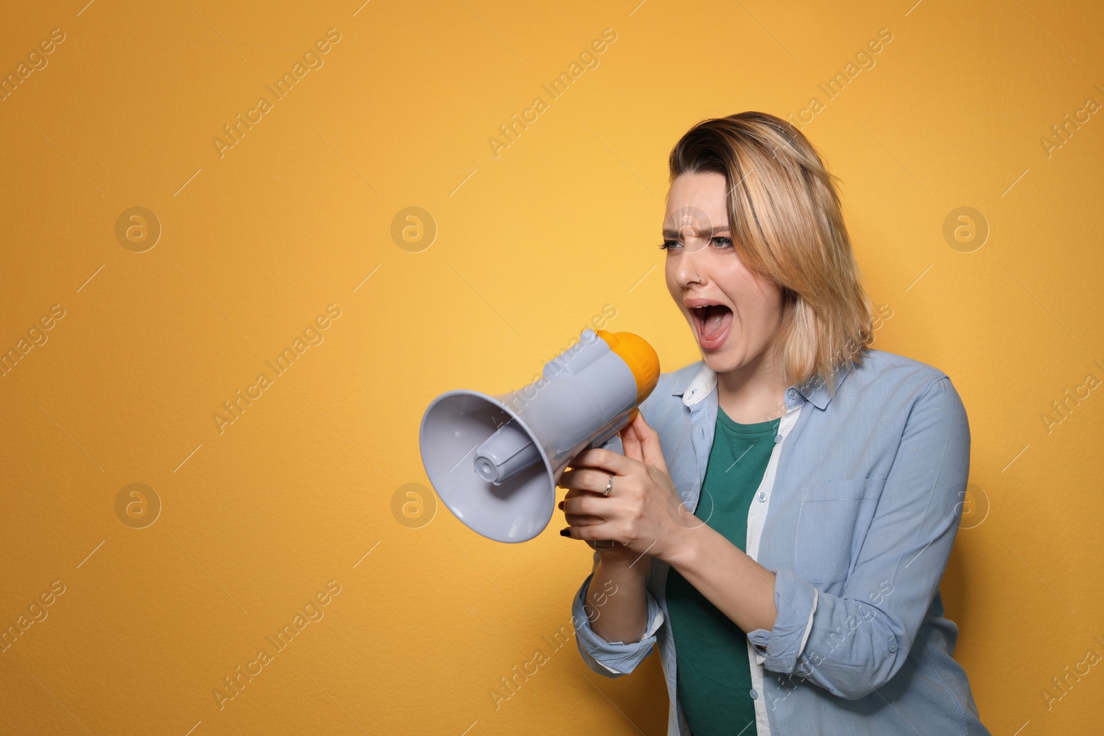 Photo of Portrait of emotional woman using megaphone on color background. Space for text