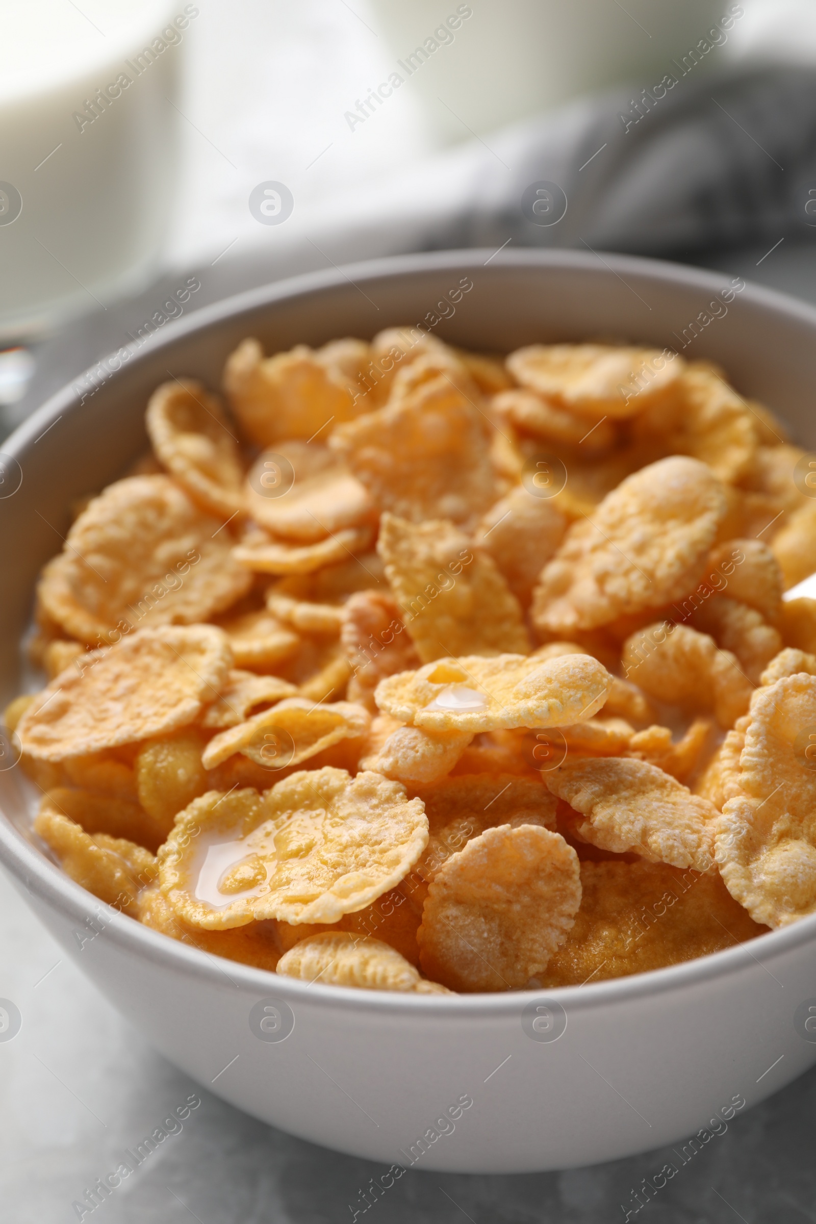 Photo of Tasty cornflakes with milk in bowl on table, closeup