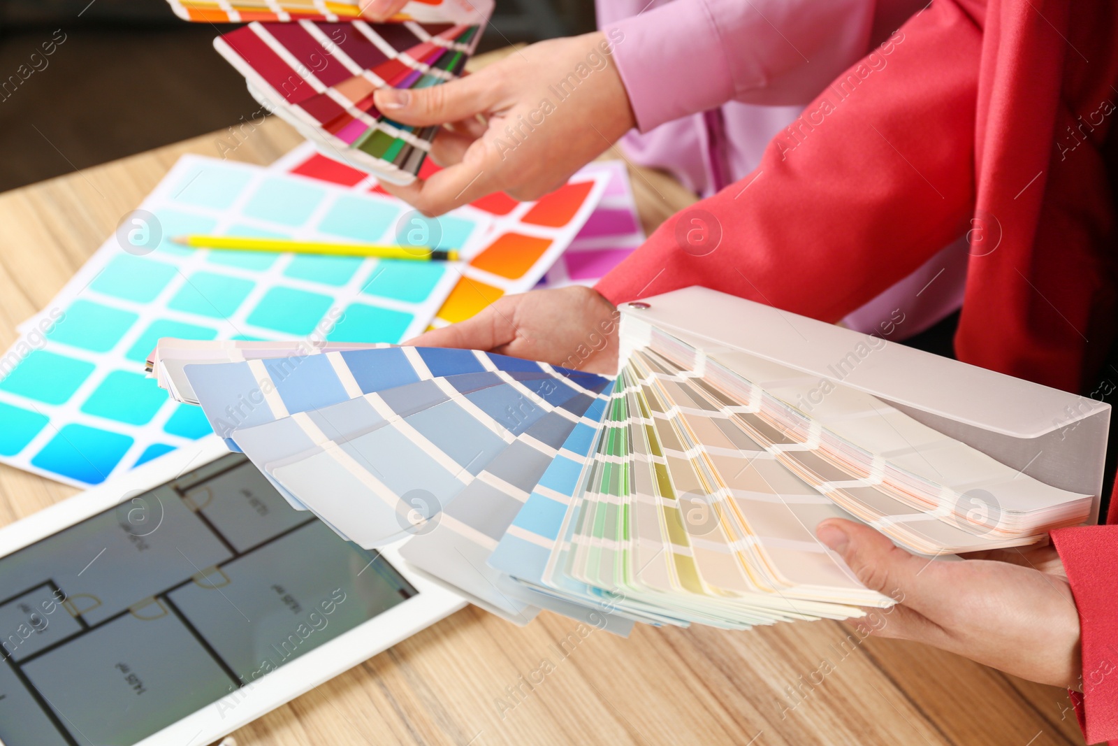 Photo of Women with palette samples at wooden table, closeup