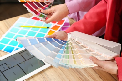 Women with palette samples at wooden table, closeup