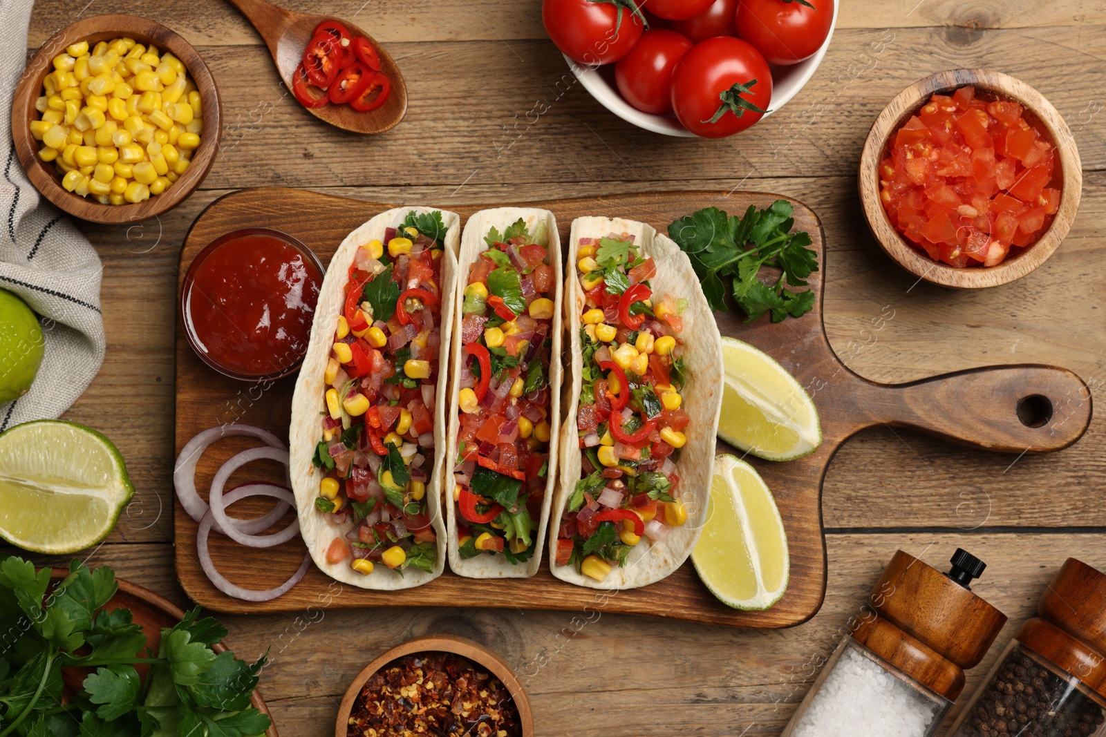 Photo of Tasty tacos with vegetables on wooden table, flat lay