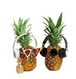 Funny pineapples with headphones and sunglasses on white background