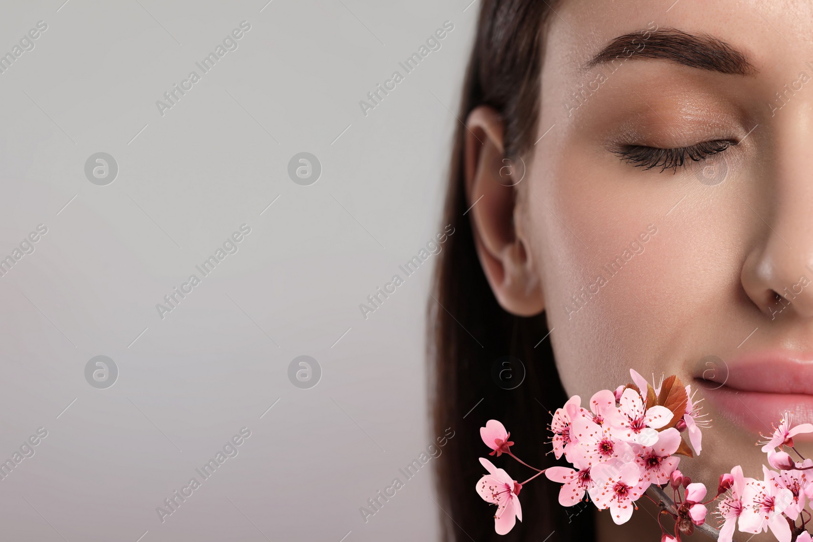 Image of Beautiful woman with smooth skin and flowers on grey background. Space for text