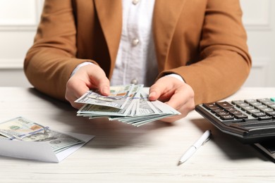 Photo of Money exchange. Woman holding dollar banknotes at white wooden table, closeup