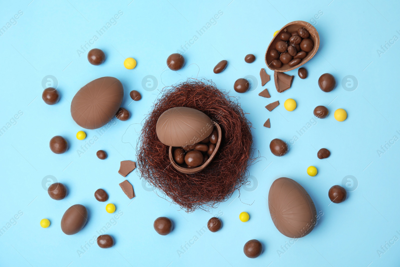 Photo of Flat lay composition with delicious chocolate Easter eggs on light blue background