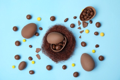 Photo of Flat lay composition with delicious chocolate Easter eggs on light blue background