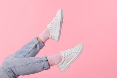 Photo of Woman wearing stylish white sneakers on pink background, closeup. Space for text