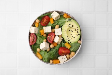 Photo of Bowl of tasty salad with tofu and vegetables on white tiled table, top view