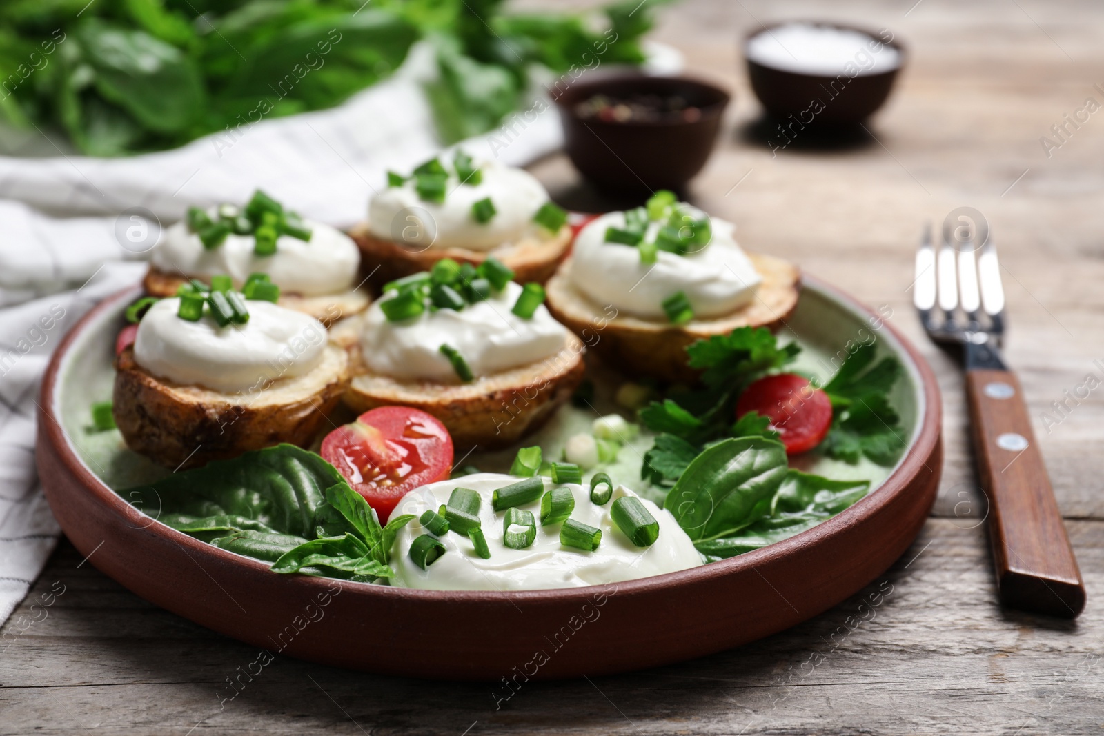 Photo of Delicious potato wedges with sour cream served on wooden table, closeup