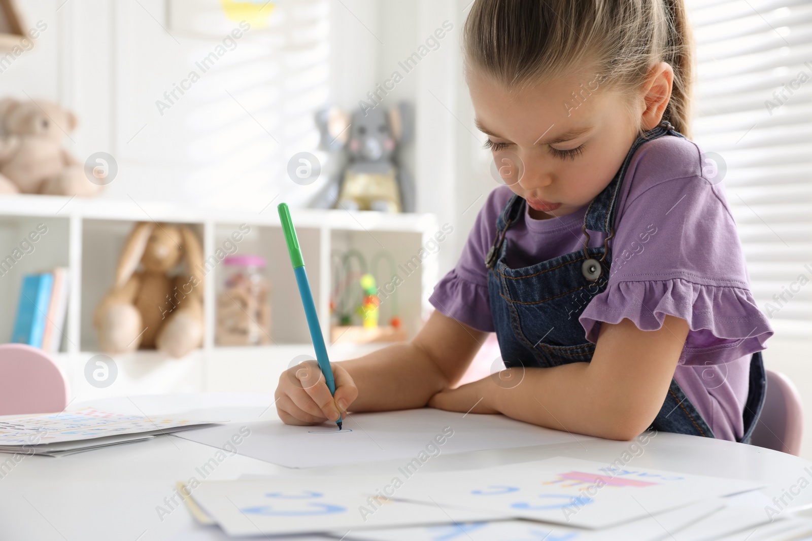 Photo of Little girl writing in classroom at English lesson