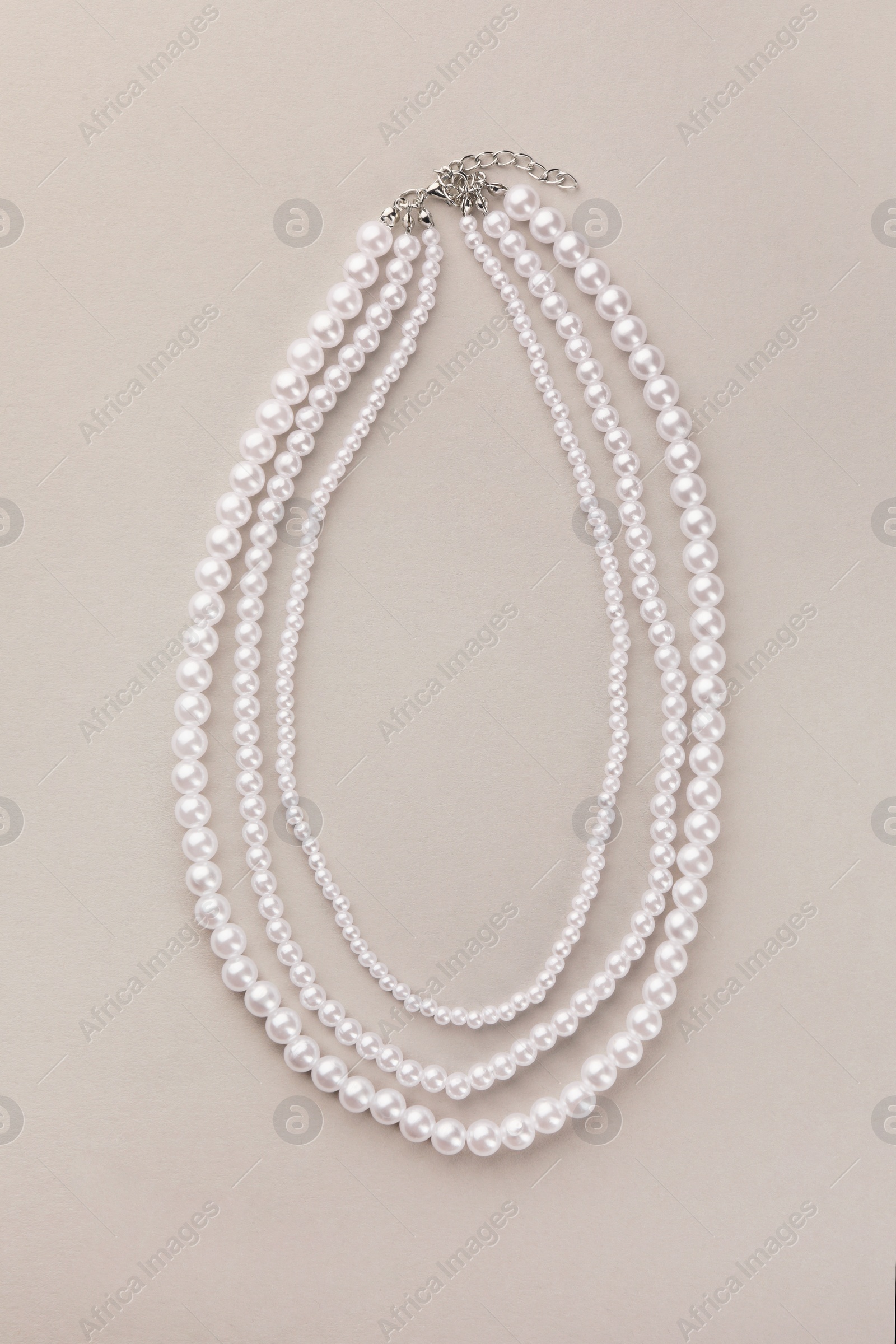 Photo of Elegant pearl necklace on beige background, top view