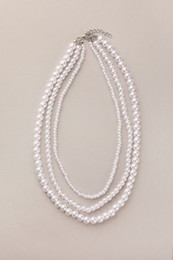 Photo of Elegant pearl necklace on beige background, top view