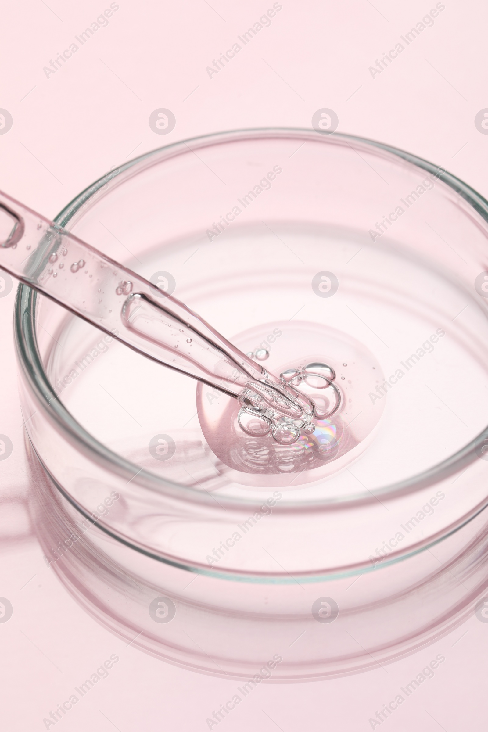 Photo of Glass pipette and petri dish with liquid on pink background