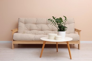 Photo of Comfortable sofa and houseplant on coffee table indoors. Interior design