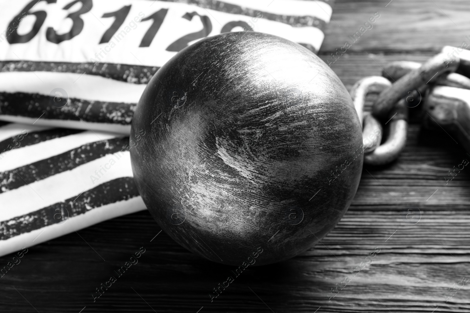 Photo of Prisoner ball with chain on black wooden table, closeup