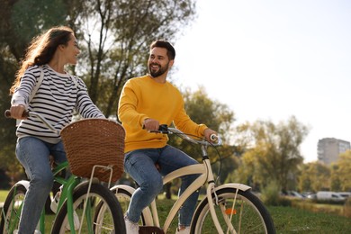 Photo of Beautiful couple riding bicycles in park, space for text