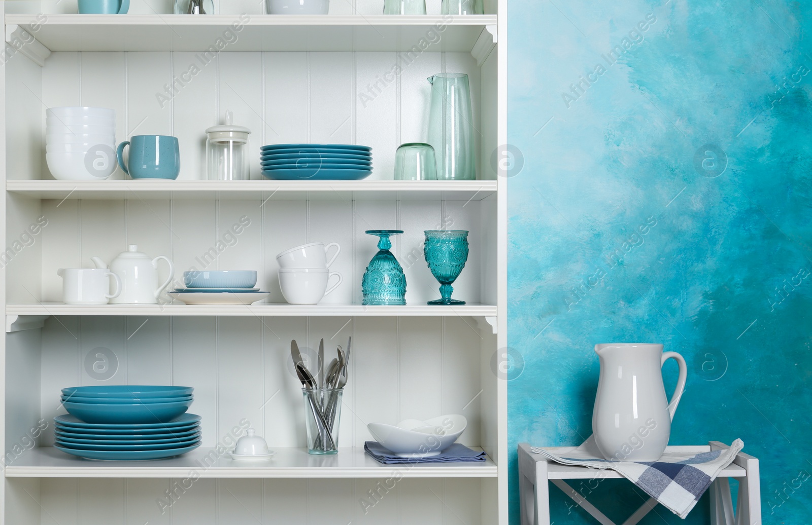 Photo of White shelving unit with set of dishware near color wall