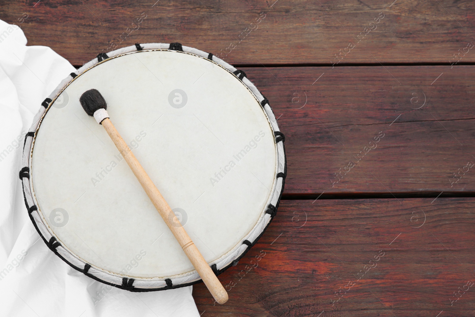 Photo of Modern drum with drumstick on wooden table, top view. Space for text