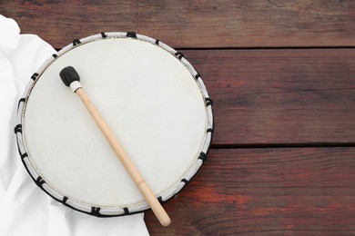 Modern drum with drumstick on wooden table, top view. Space for text