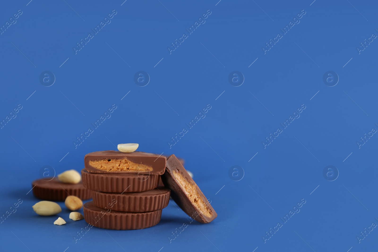 Photo of Sweet peanut butter cups on blue background. Space for text