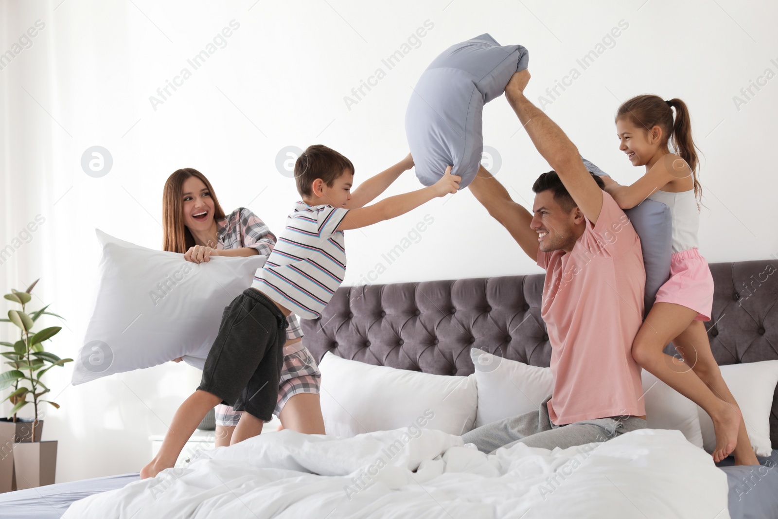 Photo of Happy family having pillow fight in bedroom