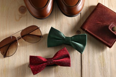 Photo of Stylish color bow ties, brown wallet, shoes and sunglasses on wooden background, flat lay