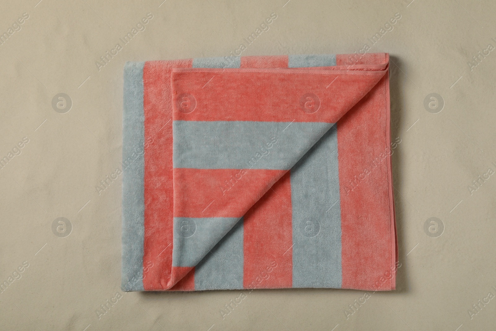 Photo of Striped beach towel on sand, top view